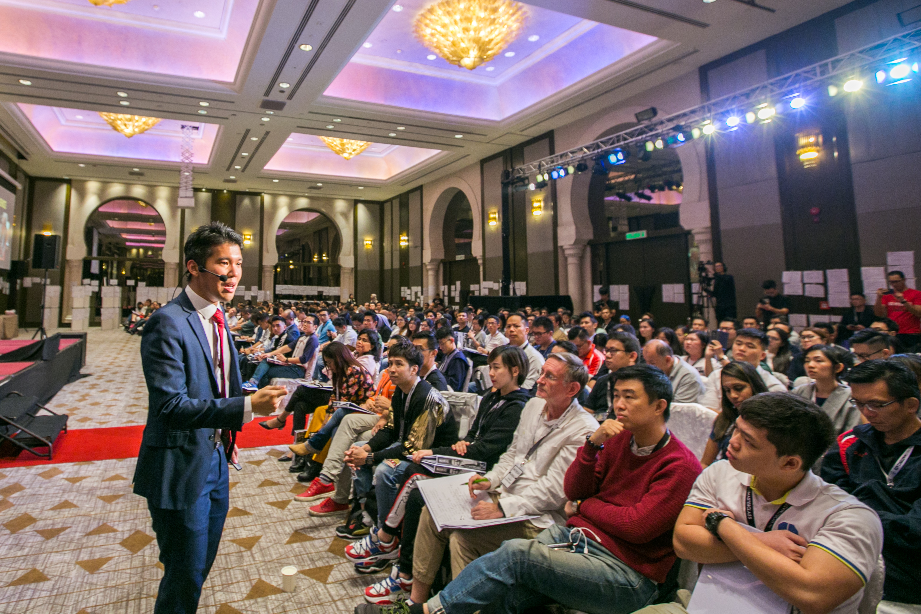 Michael Teoh speaking to a seated audience in an elegant ballroom